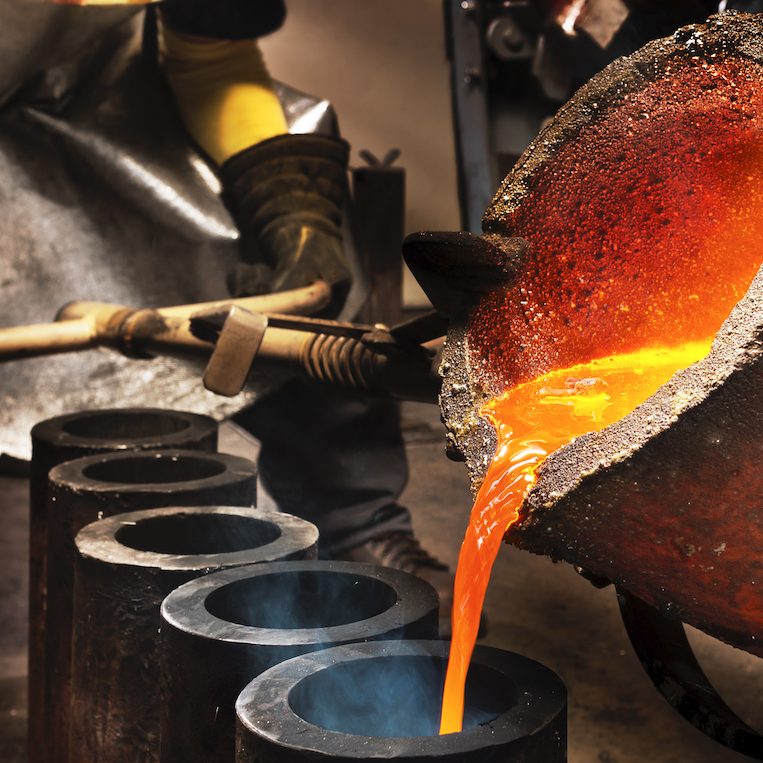 Worker pouring liquid metal into crucible.